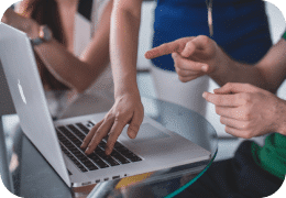 Ein Bild von einem Team von Scrum- Masters, das um einen Laptop versammelt ist, symbolisiert Skywize's Schwerpunkt auf Zusammenarbeit und Teamwork in Software-entwicklungsprojekten