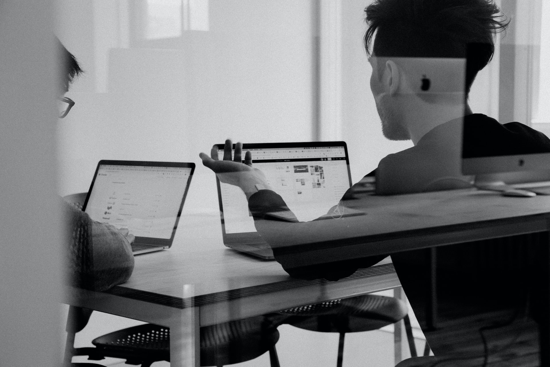 Ein Schwarz-Weiß-Bild von zwei Personen, die an einem Projekt zusammenarbeiten, stellvertretend für Skywize's Team von engagierten und erfahrenen Fachleuten im Bereich DevOps